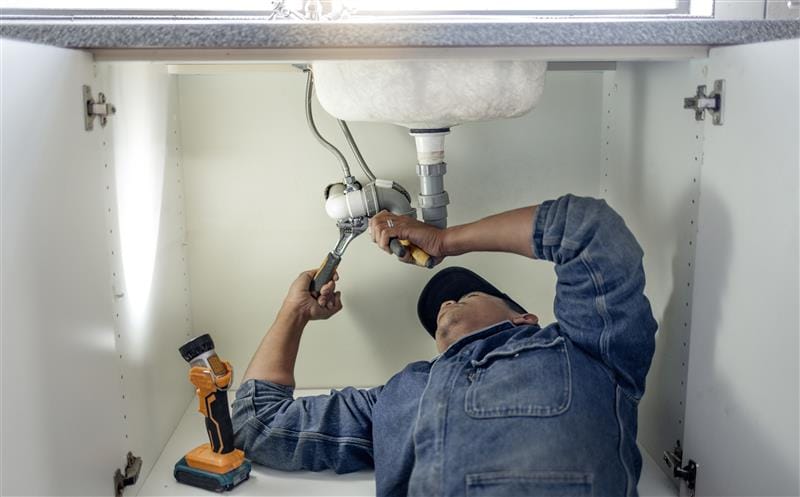 Plumber repairing kitchen sink drain pipes in Lehigh Acres, Florida