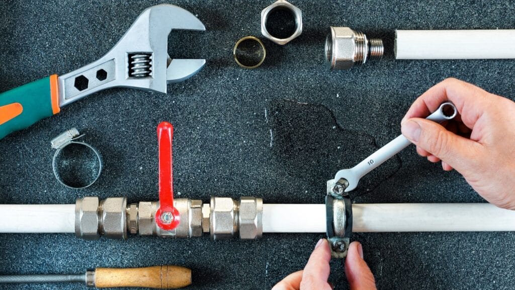 Plumber repairing a pipe valve with an adjustable wrench in Lehigh Acres