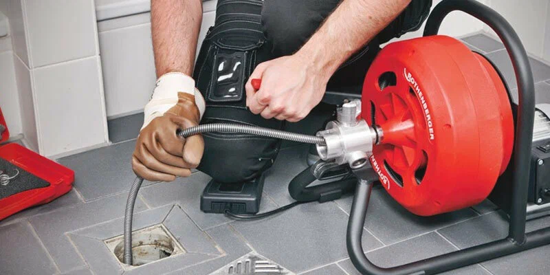 Plumber using a drain-cleaning machine in Lehigh Acres
