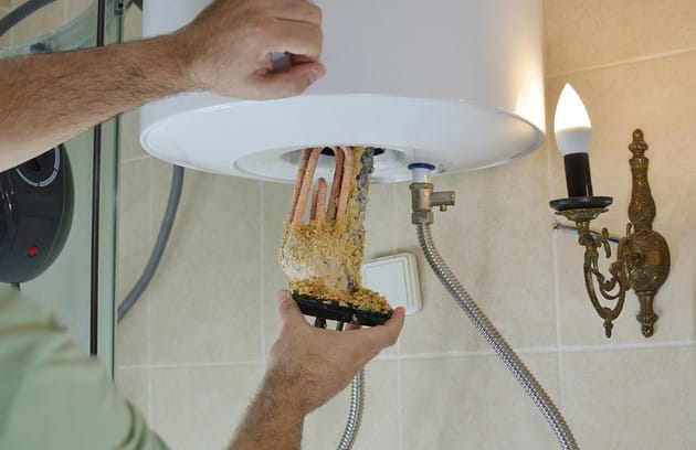 Technician removing mineral buildup from a water heater in Lehigh Acres