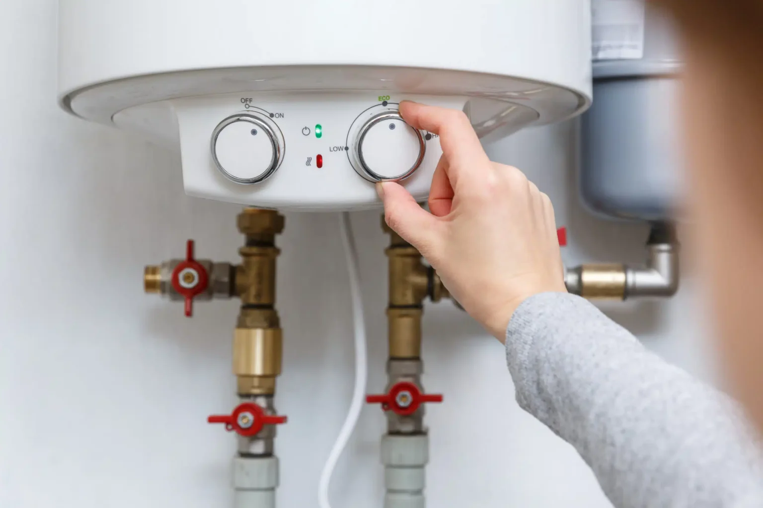 Homeowner adjusting the temperature controls on a water heater in Lehigh Acres